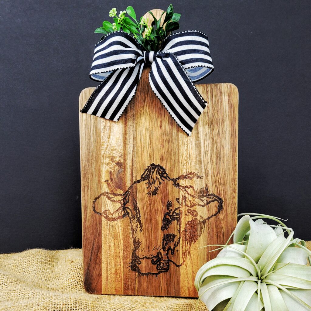 Acacia wood serving platter with laser engraved cow design for cheese, charcuterie, and appetizers.